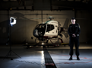 A man stands next to a bright light and a helicopter