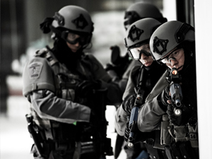 A group of officers wearing grey equipment readies their guns